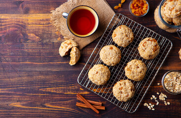 Obraz na płótnie Canvas Oat vegan cookies on cooling rack with cup of tea. Wooden background. Copy space. Top view.
