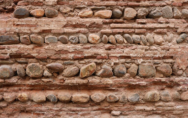 old wall background texture with ancient stones combined with damaged bricks in red, white, brown and orange colors	