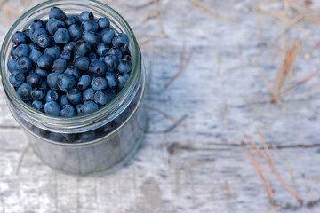 Top view of jar full of blueberry's on natural wooden forest background.