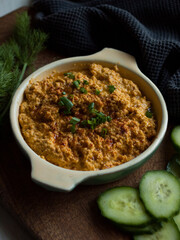 Rustic carrot hummus on wooden board.