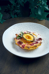 Baked cake with cherries and apricot in a white plate on a wooden background. Tasty pastry. Selective focus