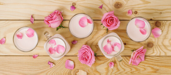 Glasses of moon milk with a roses on wooden table. Ayurvedic relaxing drink for the night.