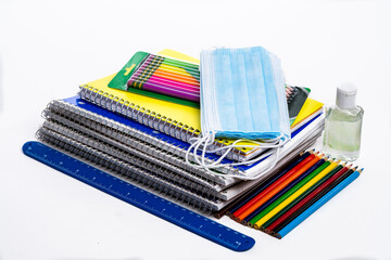 Stack of school supplies including Covid 19 face masks  on a white background