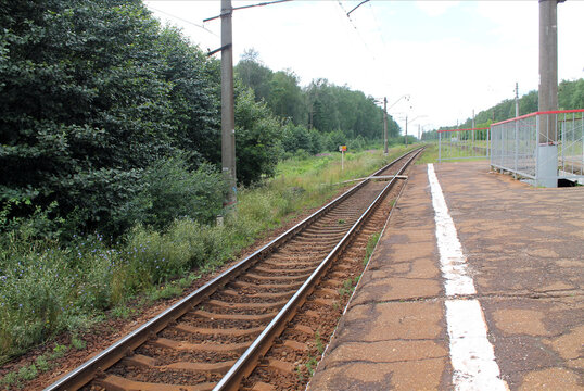 Railway platform, rails extending into the distance, waiting for a train, country landscape