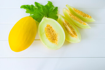 fresh ripe yellow melon melon slices on a white background view above. wooden background with whole melon and melon slices. melon close-up on the table.