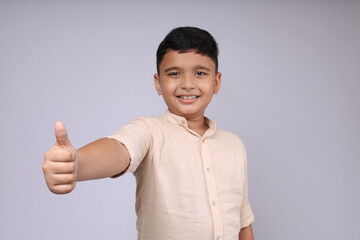 Cute Indian boy showing thumbs up or all done or like hand gesture. Isolated over white background.
