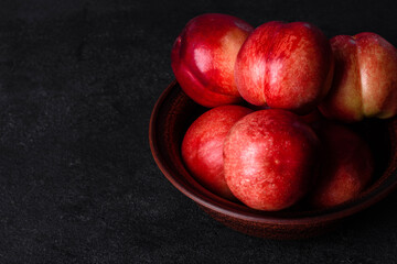 Fototapeta na wymiar Delicious sweet peaches or nectarines in a brown bowl