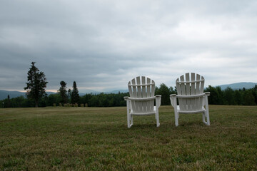 Two lawn chairs with no people positioned to overlook countryside.