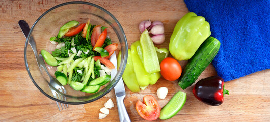 Vegetables in close-up on the cutting Board. Ripe tomatoes, cucumbers, bell peppers, parsley, garlic are sliced for a vitamin salad. The view from the top.