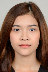 Portrait of young beautiful Asian woman against white background