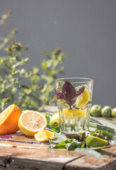 Basil smash gin alcoholic cocktail with fresh basil leaves and citrus. Studio shot of drink in freeze motion, drops in liquid splash, juice jet, slice of lime in flying. Summer cold beverage