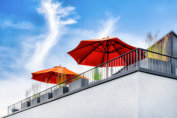 View from below on a modern outdoor terrace with orange parasols and plants