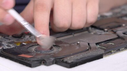 Man carefully cleans dirt and dust from laptop cooling system with soft cleaner brush, close up. Advertisement of professional repair service for electronics and devices