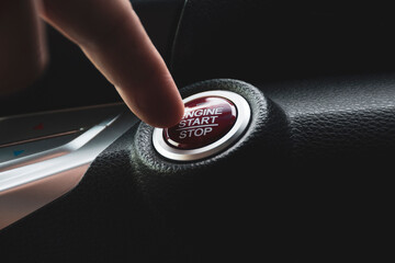 Car driver press to the engine start stop button for engine ignition in a luxury car.