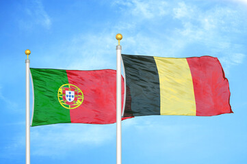 Portugal and Belgium two flags on flagpoles and blue sky