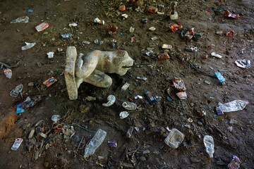 An old broken statue is lying on the ground in a pile of garbage.