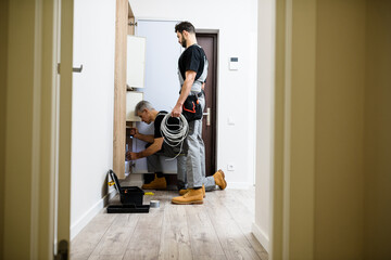 Full length shot of aged electrician, repairman in uniform working, installing ethernet cable or...