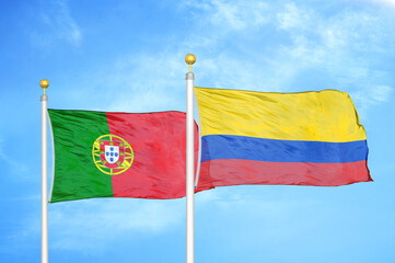 Portugal and Colombia two flags on flagpoles and blue sky