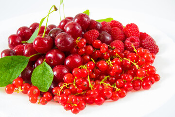 Assorted red fresh berries on a plate on a white background.