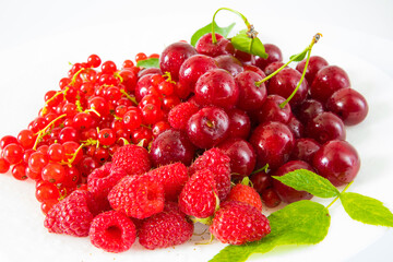 Assorted red fresh berries on a plate on a white background.