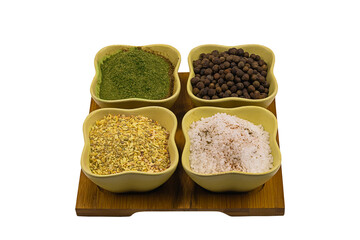 set of fragrant consists of spices in ceramic cups salt, peppercorn, dried garlic and ground parsley on a wooden tray isolated background