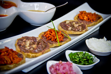 Modern Mexican Sopes with slow-cooked meats and colorful toppings served on white ceramic over a dark backdrop—authentic flavors with a gourmet twist.