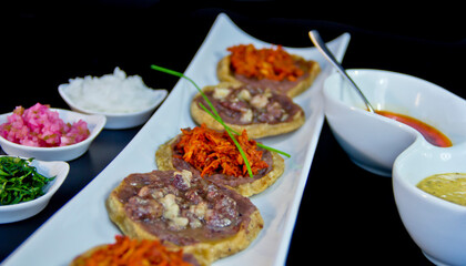Gourmet Mexican Sopes with black beans, cochinita pibil, and bone marrow—served on elegant ceramic with fresh toppings and bold salsas in a modern dining setting.