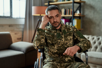 Feeling lonely. Middle aged thoughtful military man in a wheelchair looking away during therapy...