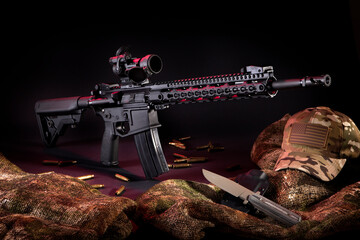 Dramatic studio lighting of an AR-15 Rifle with rounds, a knife and gear.