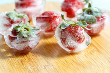 fresh strawberries frozen in ice cubes, close-up. blurred background
