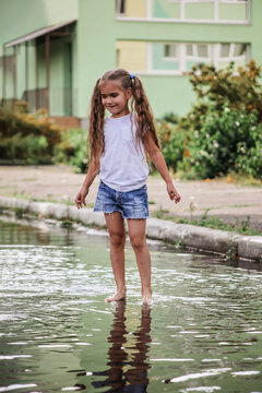 Cute happy kids jumping in the puddles after warm summer rain, lifestyle outdoor
