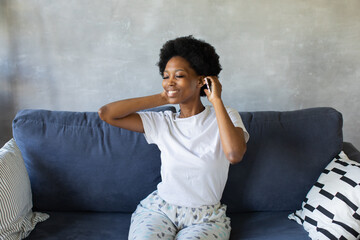 African American girl dancing with her phone on the couch in a cozy room