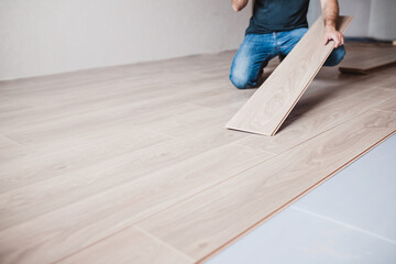 Man in jeans on a new laminate floor - wood floor decor - laminate laying master