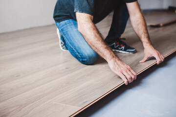 The master mounts the laminate on the floor - a long row assembled from panels along the entire length joins the previous one