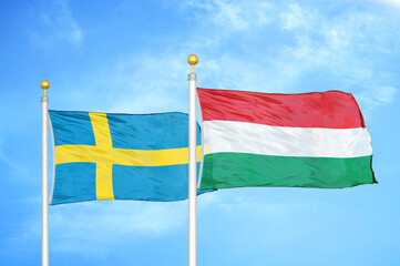 Sweden and Hungary two flags on flagpoles and blue sky
