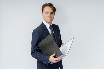 A businessman in a blue suit holds folders on a white background.