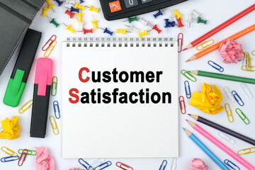 On the table is a calculator, diary, markers, pencils and a notebook with the inscription - Customer Satisfaction