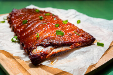 Close up board with pork ribs grilled with BBQ sauce, peanuts and jalapeno