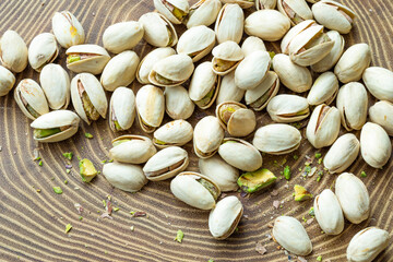 Roasted pistachios seeds with open shell placed on wooden backdrop