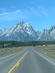 Driving on an empty highway with the Grand Teton mountains in the background