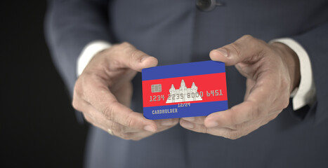 Businessman holding plastic bank card with printed flag of Cambodia, close-up shot, fictional numbers