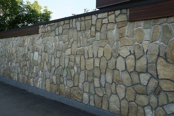 long gray brown stone fence wall outdoors on asphalt