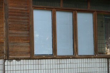 one large window with white closed shutters on the brown wooden wall of the building