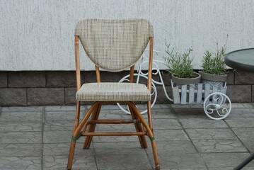 one brown wooden chair with a soft seat stands on a gray sidewalk outside in a summer cafe