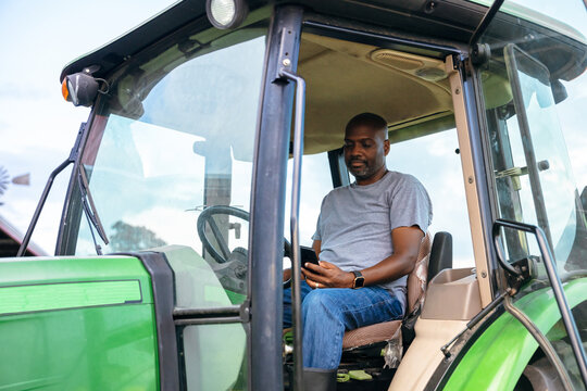 Man sitting on tractor checking smartphone 