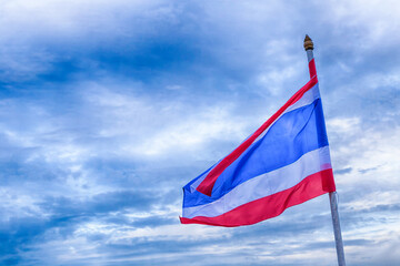 the flag of Thailand with red, blue and white stripes is fixed on the flagpole, develops against the background of a dark stormy sky
