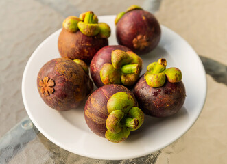 Whole fruits Mangosteen fresh and delicious Asian fruits lie on a white plate
