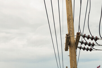 electric wires parallel strung on a pole against a cloudy sky, has copy space