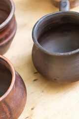 dark brown clay pot, traditional homemade utensils close-up on wooden background