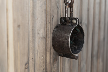 old rusty and forged shackles closeup hanging on a wooden wall